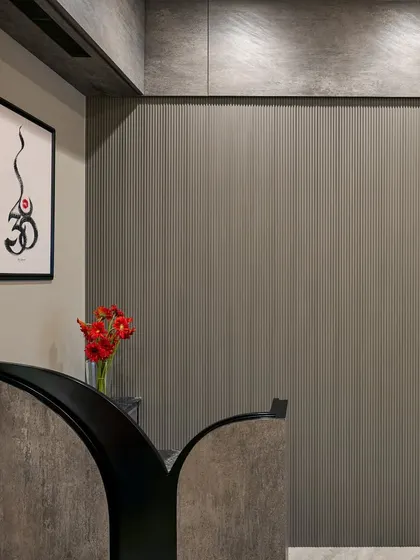 The reception area features a textured grey wall and a custom-designed desk. A piece of calligraphy art adds a spiritual and personal touch, making a great first impression.
