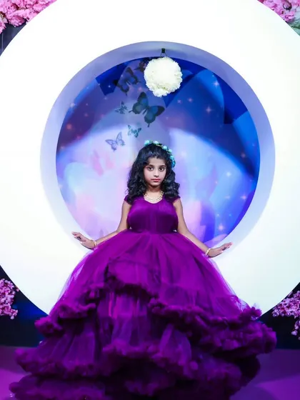 A magical portrait of a young girl in a purple gown, seated in our moon-shaped prop against a celestial butterfly backdrop.