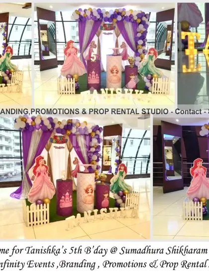 This simple princess theme for a 5th birthday at Sumadhura Shikharam showcases an elegant setup with a white curtain backdrop and a lavender and gold balloon arch. Themed cylinder tables featuring different princesses and marquee letters add a personalized and magical touch.