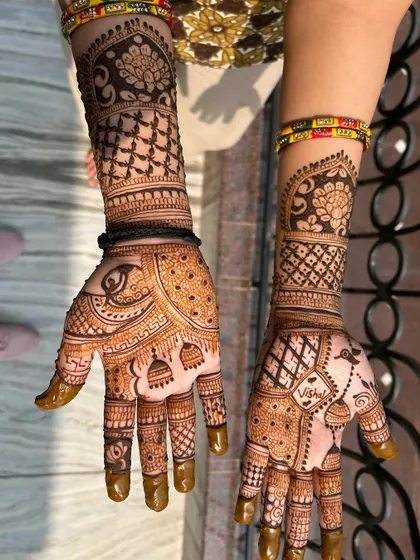 The complete Karwachauth design with the name 'Vishal' integrated into the pattern. The fingertips are fully covered for that deep, traditional stain.