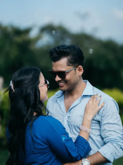 A cool and casual pre-wedding portrait of a couple in sunglasses, sharing a smile as bubbles float around them.