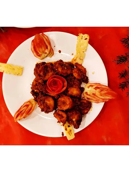 My Chilly Prawns are simply the best. This top-down shot shows the beautiful presentation with a tomato rose, highlighting the rich, glossy sauce and perfectly cooked prawns.