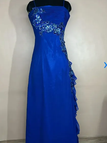 This royal blue bodycon dress features beautiful floral embroidery and a side ruffle. It's an elegant and sophisticated choice for a formal event or photoshoot.