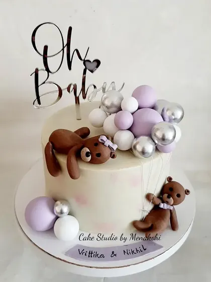 A baby shower cake in hues of silver and lavender to match the party decor. The design features cute teddy bears and balloon decorations.