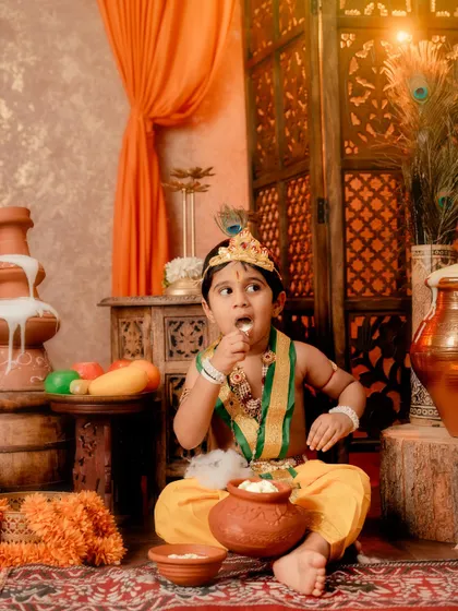 This young Krishna is caught in the act, enjoying a pot of butter in a playful and candid moment.