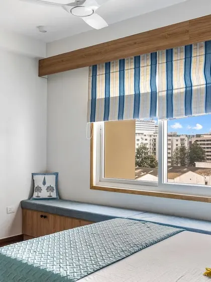 A shot of the cozy bay window seat in the 'Tatvam' kids' room, complete with storage underneath and cheerful striped blinds.