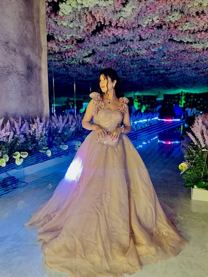 A full view of the champagne gown, showing its flow and elegance. The floral shoulder details add a soft, romantic touch to this glamorous outfit.