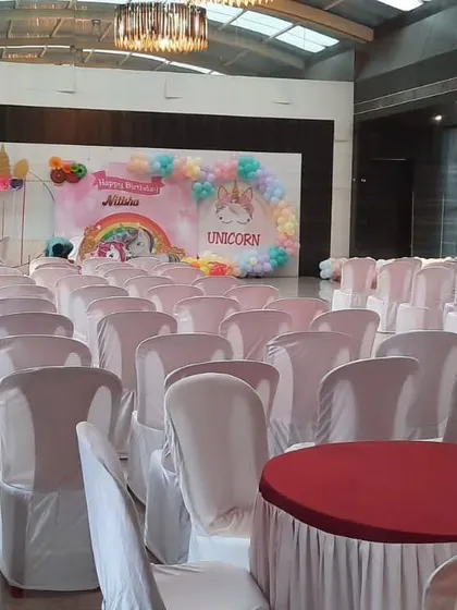 A unicorn-themed birthday party in a large hall. The pastel-colored backdrop and balloon decorations create a magical atmosphere for the celebration.