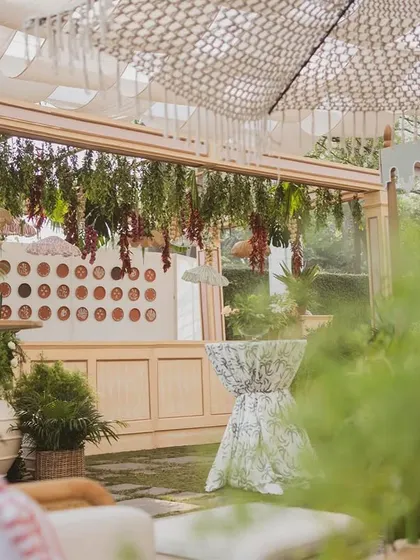 A bar area at the 'Farmers Market' brunch, with a canopy of hanging greenery and dried vegetables, reinforcing the rustic theme.