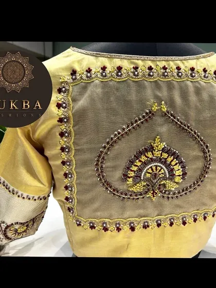 An elegant sheer back design on a golden blouse. A beautiful heart-shaped motif is embroidered in the center, creating a focal point that is both unique and sophisticated.