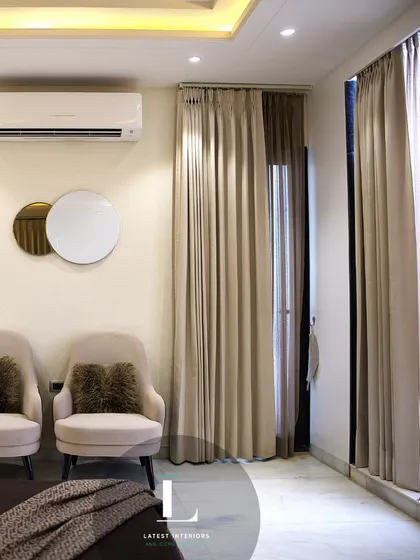 This shot highlights the cozy reading nook by the window, complete with two comfortable armchairs. The full-length curtains can be drawn for privacy or opened to let in natural light.