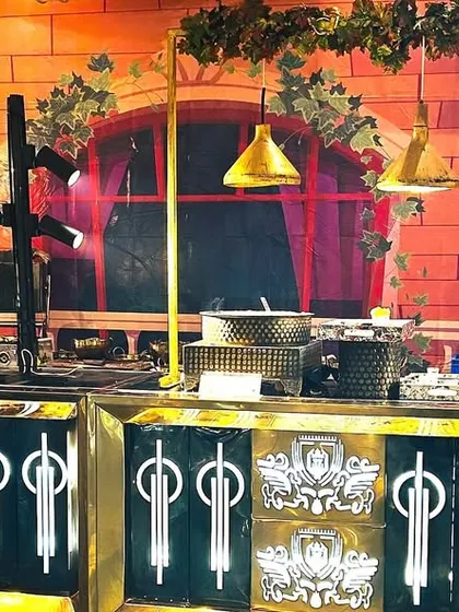 The backdrop can change the entire vibe of a food station. Here, a European street-style backdrop complements our ornate black and gold counters, transporting guests to a different world.