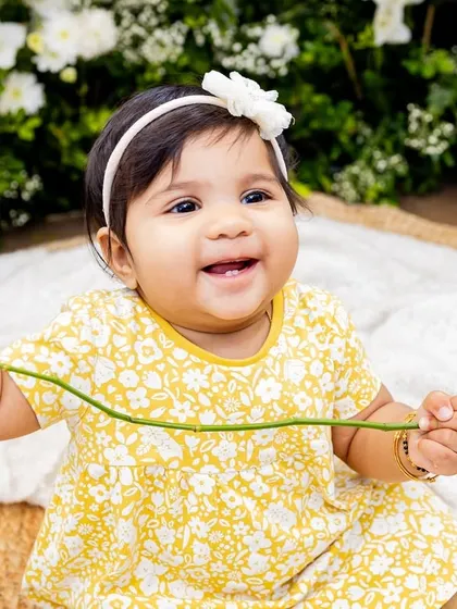 A sweet baby girl holding a flower, captured in timeless black and white.