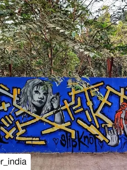 A tribute to the metal band Slipknot, featuring their iconic masks alongside complex yellow lettering on a bright blue wall. A great example of subculture representation in street art.