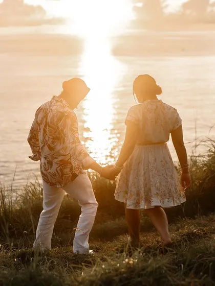 A beautiful silhouette of a couple walking towards the sunset on a cliffside in Thailand, a perfectly romantic and cinematic shot.