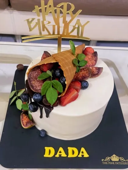 A unique take on a fruit cake, with a waffle cone spilling fresh figs, blueberries, and strawberries over the top.