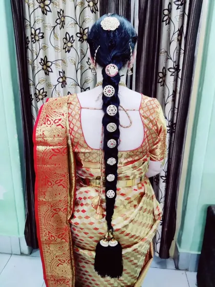 A traditional long braid for bride Jaylakshmi's Varapooja ceremony. This hairstyle features classic round, coin-style hair ornaments placed neatly along the length of the braid.