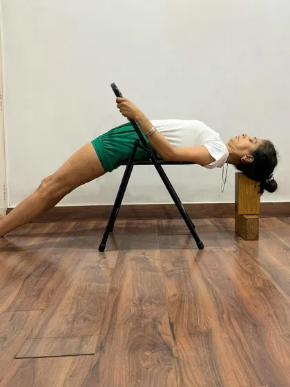 This supported Purvottanasana variation uses a chair and blocks for head support. It allows for a longer hold, enabling the practitioner to relax into the pose and experience its restorative benefits.