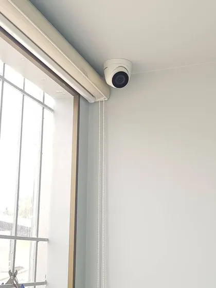 A Hikvision dome camera installed indoors near a window, providing surveillance of the room.