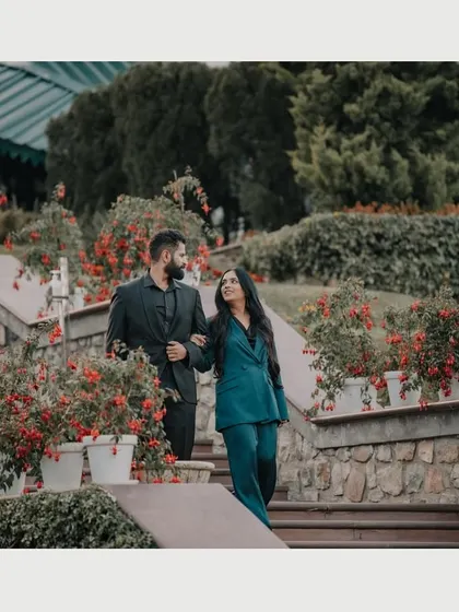 A couple shares a walk down a flower-lined staircase in the hills. This candid shot captures the elegance and romance of a pre-wedding session in a picturesque mountain resort.