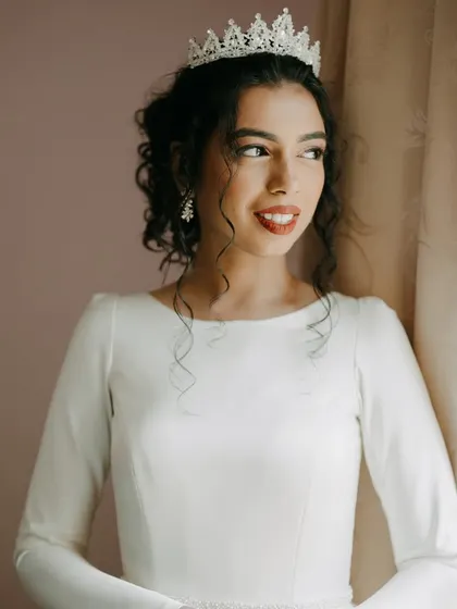A beautiful window-lit portrait. Her natural curls are styled perfectly, and her red lip adds a touch of classic glamour.