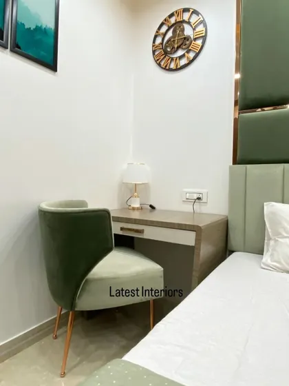 A close-up of the study corner, featuring a simple yet elegant desk and a comfortable green velvet chair with rose gold legs.