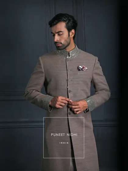 A statement in subtle royalty, this brown matka silk achkan features a jeweled collar and cuffs. It is sophisticated, graceful, and enduring.