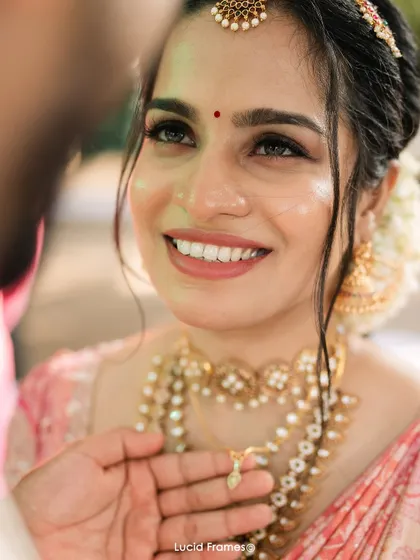 A close-up on the bride's emotional and happy expression as the groom presents her with the thaali.