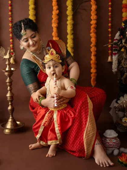 A curious baby Krishna tastes his flute while sitting comfortably with his mother.
