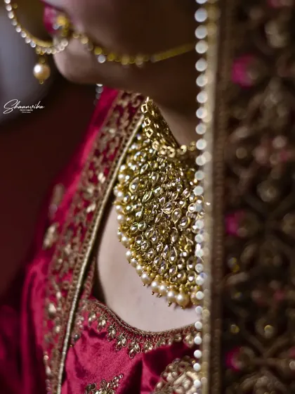 A close-up, artistic shot of the bride's magnificent gold necklace, showing the intricate craftsmanship of her wedding jewelry.