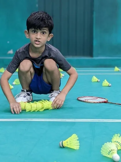 A moment of focus as a junior player neatly stacks shuttlecocks. This simple task teaches organization and respect for the equipment and the game.