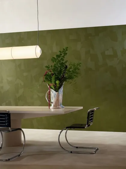 In this dining space, the Dédales wallcovering in olive green creates a backdrop of textured simplicity. The embossed grooves, mirroring an artisan's touch, revive the ancient mastery of plasterwork in a contemporary way.