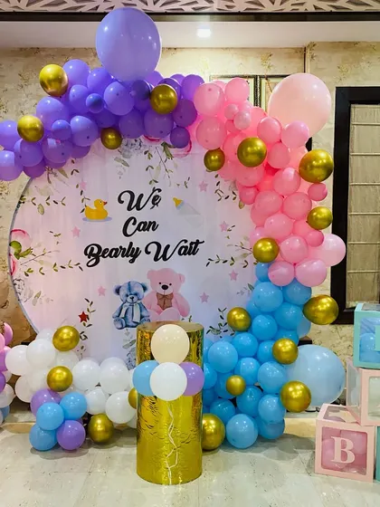A "We Can Bearly Wait" teddy bear themed baby shower. The decoration includes a custom circular backdrop and a colorful balloon arch in pink, purple, and blue.