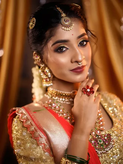 This portrait highlights the complete styling, from the maang tikka and nose ring to the layered necklaces. Every element is carefully considered to create a cohesive bridal look.