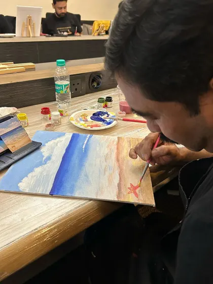 A close-up of a participant carefully painting a starfish on his beach canvas. The small details make the art personal.