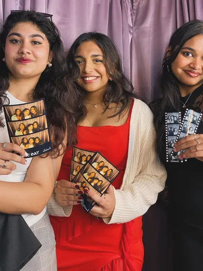 Friends showing off their different photo strips, some in the classic filmstrip style and others with a custom "Ethnic Day" design.