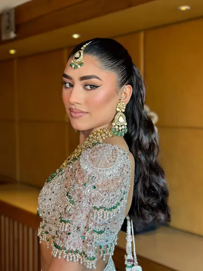 A side profile showcasing the sharp ponytail and the clean lines of the makeup. This look is for the bride who is confident and loves a modern aesthetic.