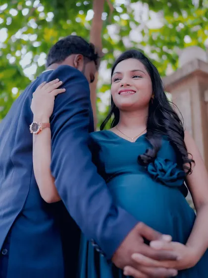 A beautiful outdoor shot of a couple during their maternity shoot. The mom-to-be is wearing a lovely teal blue gown.