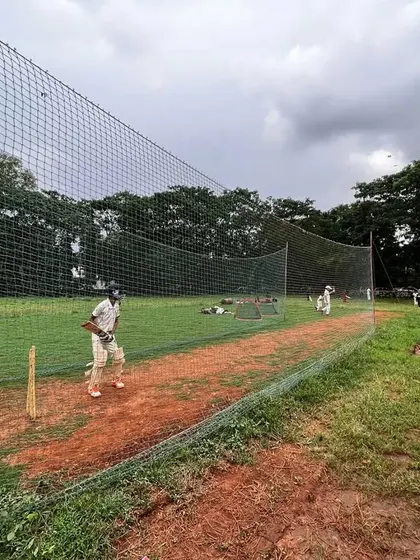 A player ready in his stance during an outdoor net session. The natural turf and soil pitches at our Kharghar ground provide an authentic practice experience.