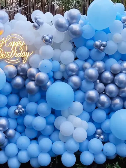 A cool and refreshing balloon wall in shades of blue, white, and silver. This 'Frozen' inspired backdrop with a 'Happy Birthday' neon sign is perfect for kids' parties or anyone who loves a winter wonderland theme.