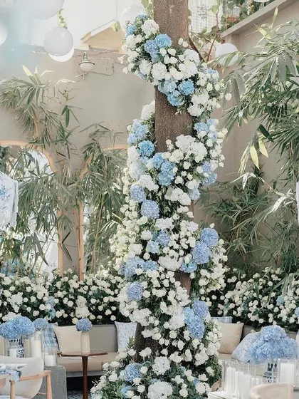 A tree trunk wrapped in a spiral of blue and white hydrangeas for Alanna Panday's baby shower, creating a stunning floral installation.