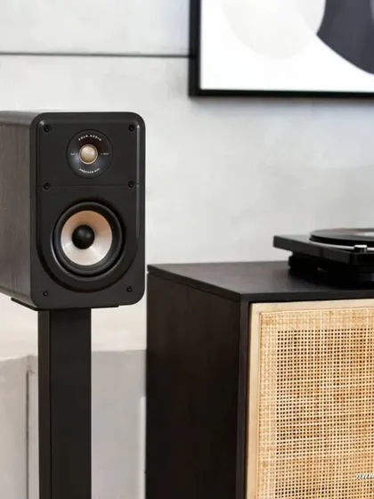 The Polk Signature Elite ES15 bookshelf speaker, shown on a stand. This compact speaker delivers the same high-resolution audio and detailed sound as its larger counterparts.