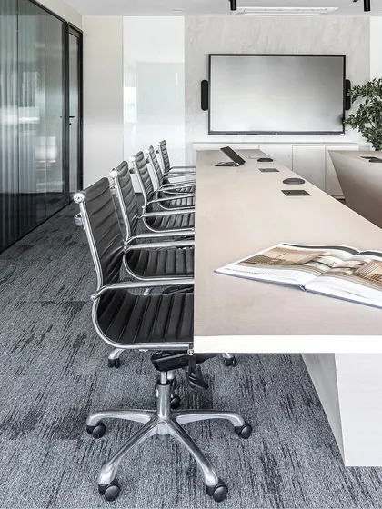 We designed the conference rooms to be light and airy, using beige tones to complement the office's grey palette. The U-shaped table maximizes seating and personal space while maintaining an open feel.