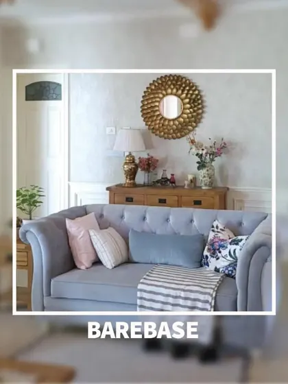 A snapshot of a cozy living room corner, where a classic sofa is styled with soft pillows against a backdrop of a gold sunburst mirror and wooden console.