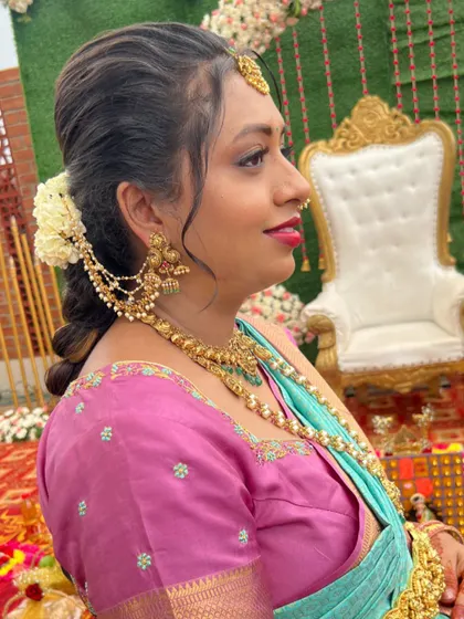 A side profile showing the beautiful hairstyle and traditional ear chains for Jayasudha's baby shower look.