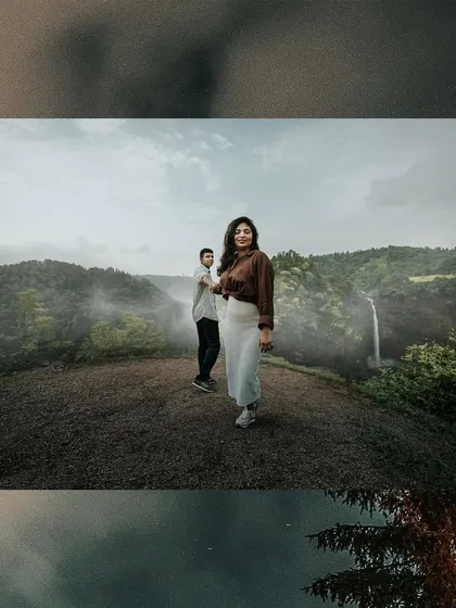 A wide, panoramic-style shot of a couple on a hilltop, with a misty valley and waterfall creating a breathtaking pre-wedding backdrop.