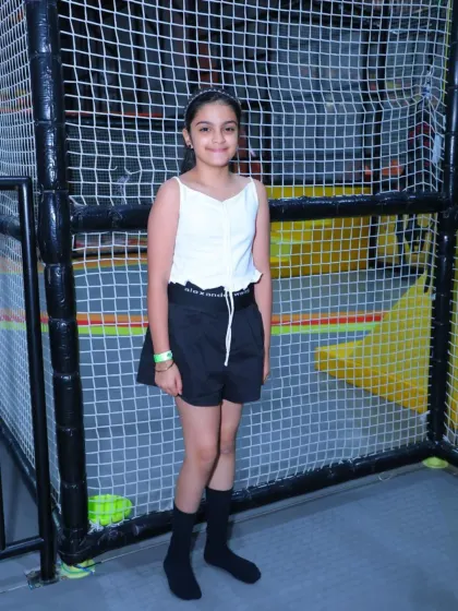 A young girl poses confidently by the safety netting of our play structures.