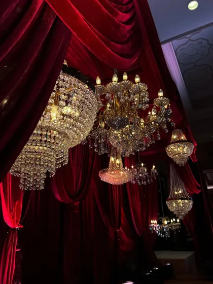 The interplay of light and shadow on the crystal chandeliers and red drapes. We use lighting to highlight the richness of the materials and create a multi-layered visual experience.