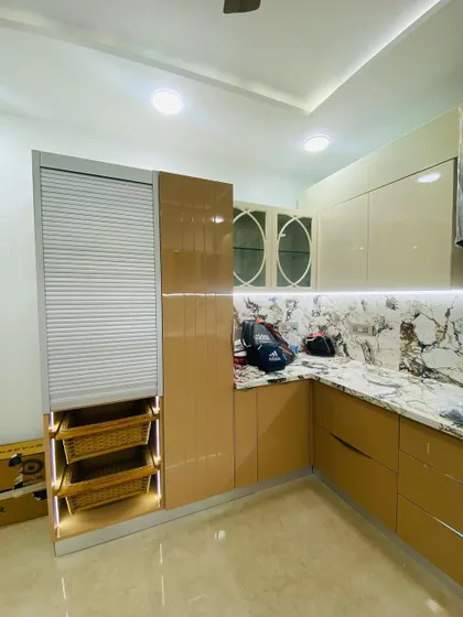 This kitchen features a rolling shutter unit with integrated wicker baskets for vegetable storage. The oval-windowed display cabinets add a unique design touch.