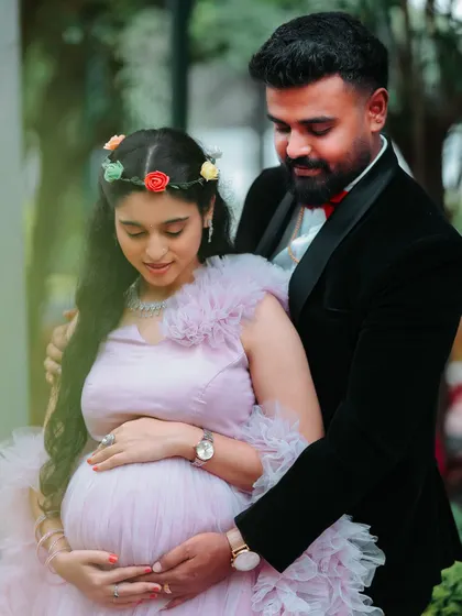 A close-up showing the beautiful details of this maternity shoot. The mom-to-be wears a flower crown that complements her ruffled pink gown, adding a soft, bohemian touch.